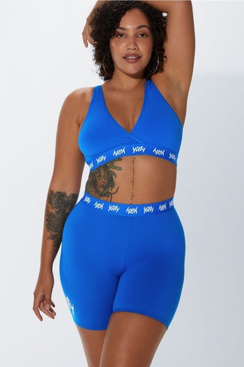 a model wearing the shorts in a royal blue with a matching bra top