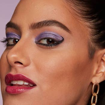 model wearing purple eyeshadow with black liner under their eye