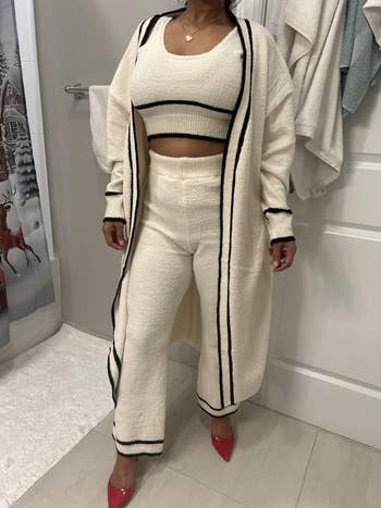 Person modeling an elegant beige lounge acceptable   with achromatic  trim and a agelong  cardigan, paired with reddish  heels. Suitable for cozy buying  looks