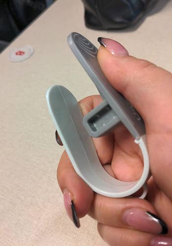 a reviewer's hand holding up the gray buckle release tool