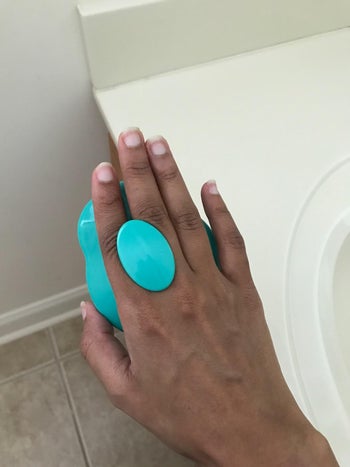 reviewer showing the other side of the teal shampoo brush