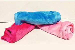 two pink and a blue towel rolled up stacked on each other