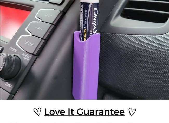 person placing tube of ChapStick in the purple holder on their car dash