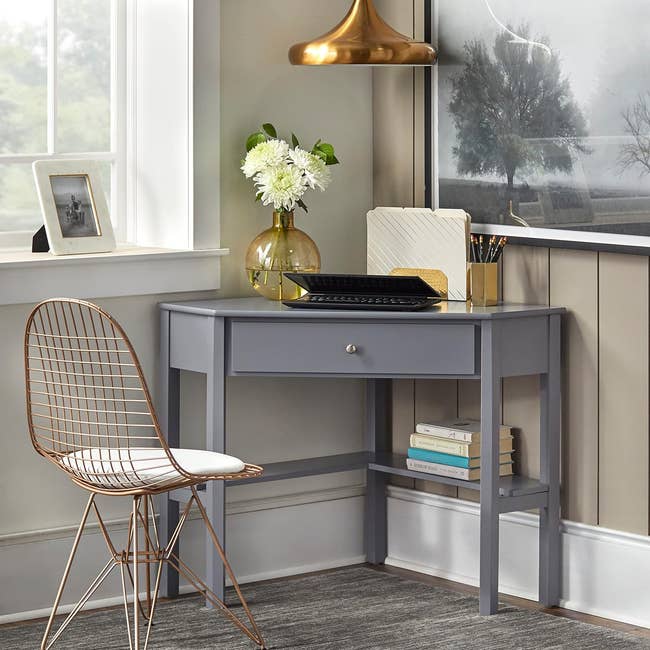 A home office setup with a sleek gray desk, gold wire chair, and brass lamp, ideal for a modern workspace
