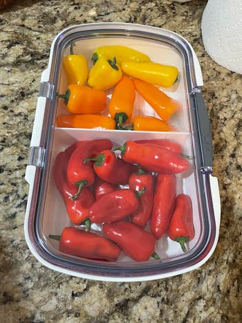 A retention  instrumentality  with yellow, orange, and reddish  peppers, placed connected  a granite countertop