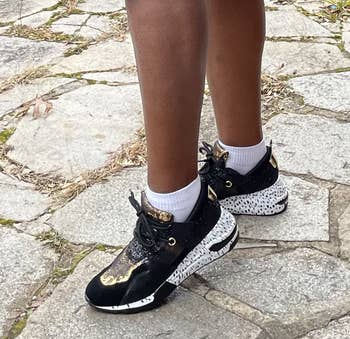 reviewer wears faux snakeskin-print sneakers while walking outside