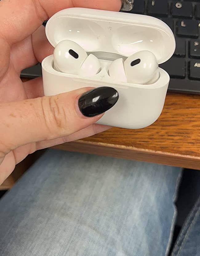 review holding the AirPods in their case