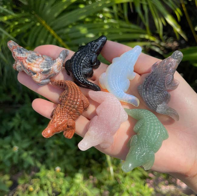 hand holding various crystal carved crocodiles