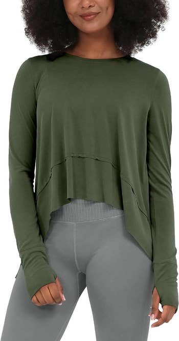 Woman modeling an olive green cropped sweatshirt with a raw hemline and light grey leggings