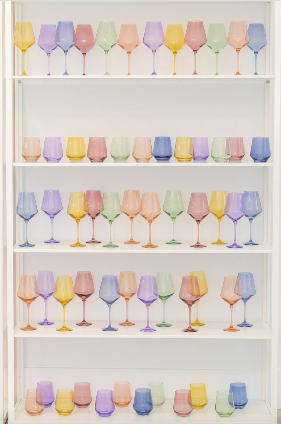 A variety of colored glassware sits inside a white display cabinet