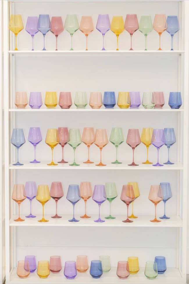 A variety of colored glassware sits inside a white display cabinet