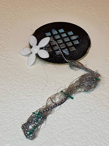 reviewer image of hair attached to the hair catcher on the drain wig