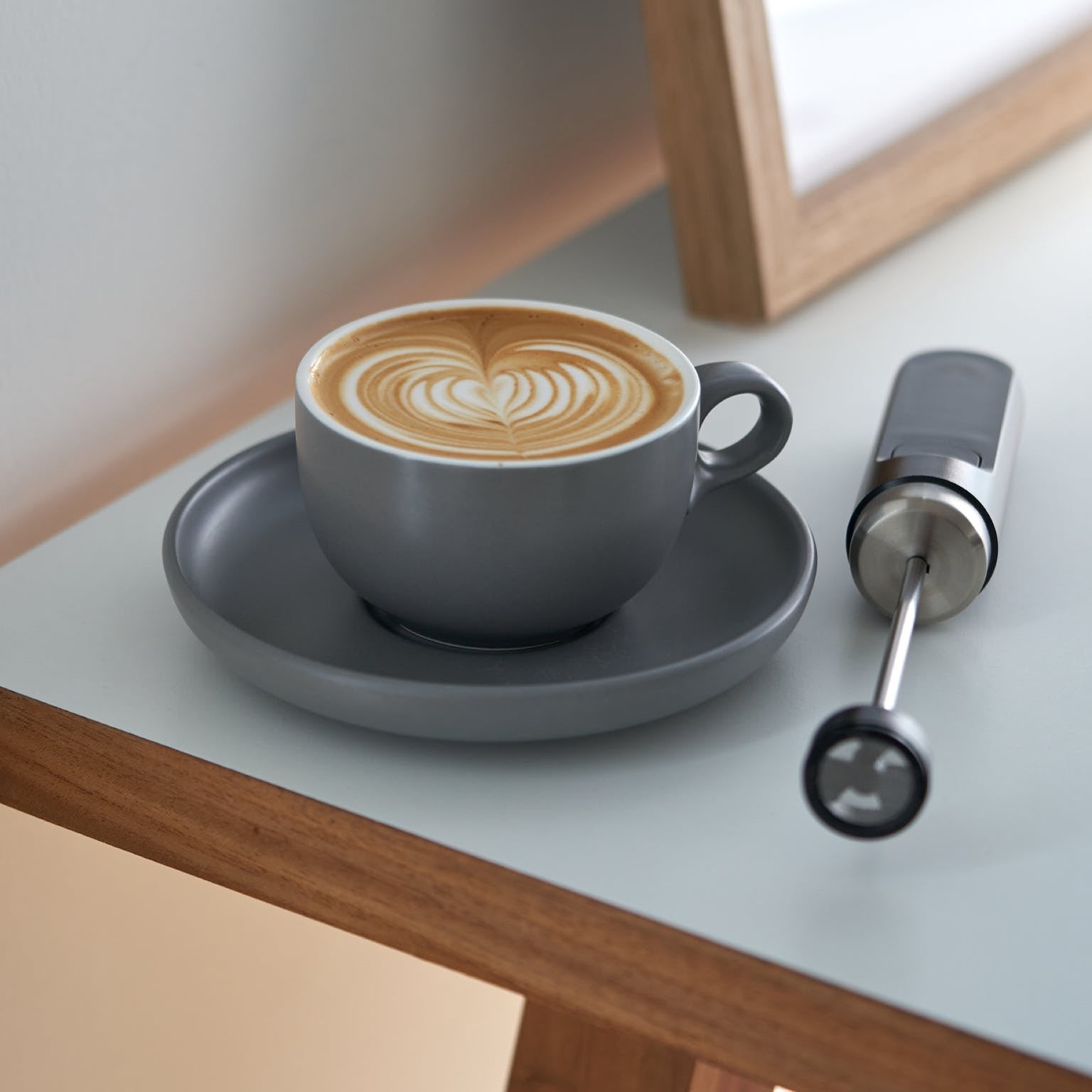 frother next to a latte with latte art foam