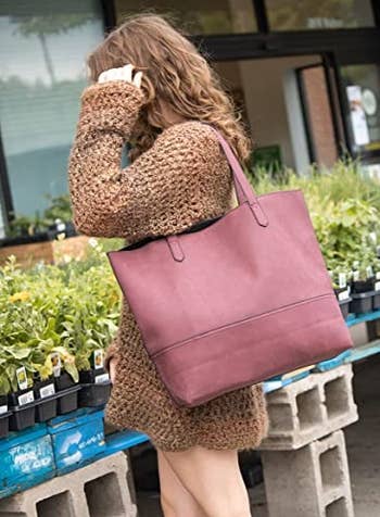 a model wearing the tote in burgundy on their shoulder 