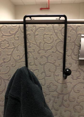 a dual-hook unit mounted on a cubicle wall with a coat hanging from one of the hooks 