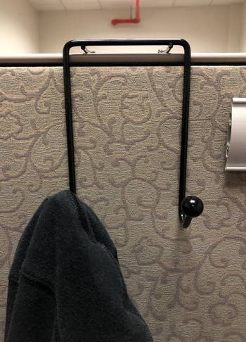 a dual-hook unit mounted on a cubicle wall with a coat hanging from one of the hooks 