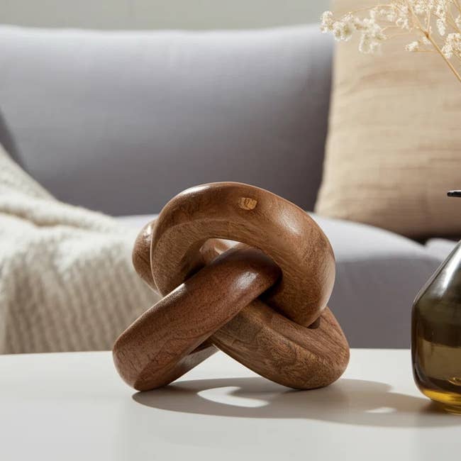 Wooden knot sculpture on a coffee table, with a cozy sofa and neutral-toned decor in the background