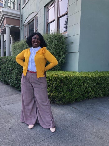 reviewer wearing the red plaid version with a white button down and yellow cardigan