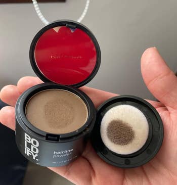 a reviewer holding the compact powder with sponge applicator