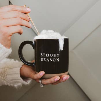 Person holding a mug labeled 