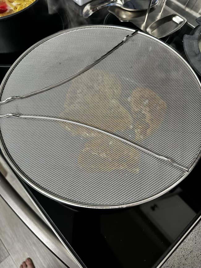 Stovetop with a splatter surface covering a pan, preventing lipid splashes during cooking successful a room setting