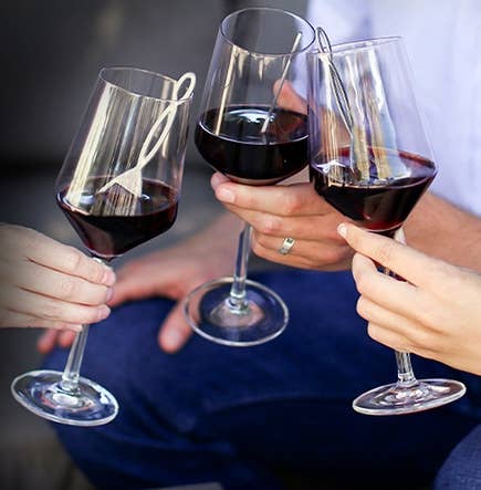 three people holding wine glasses with filters inside
