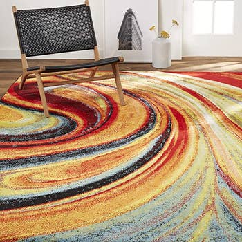 A chair on top of a color rug with swirls of colors