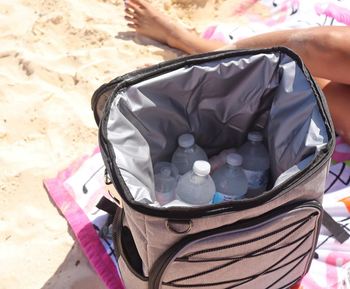 Reviewer shows open white cooler of water bottles while sitting on a beach blanket