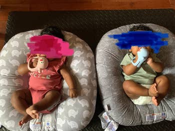 reviewer's photo of their twins using the penguin pacifiers