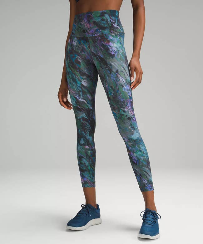 model wearing the leggings in blue, green, and purple pattern