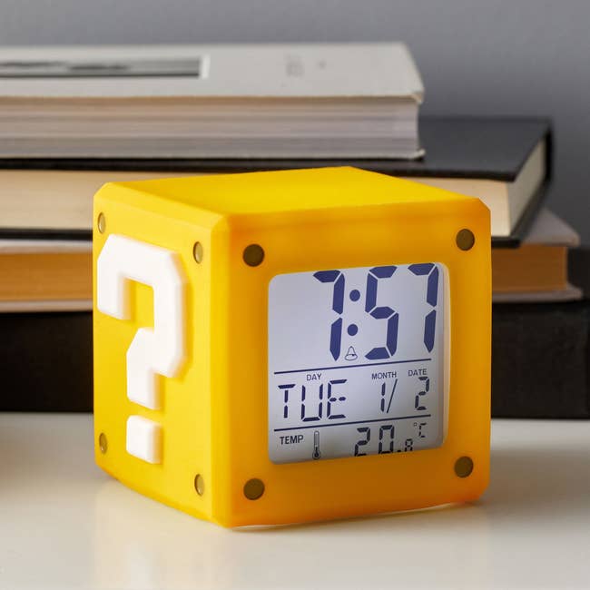 digital alarm clock that looks like yellow question mark block from mario games and features time date and temperature