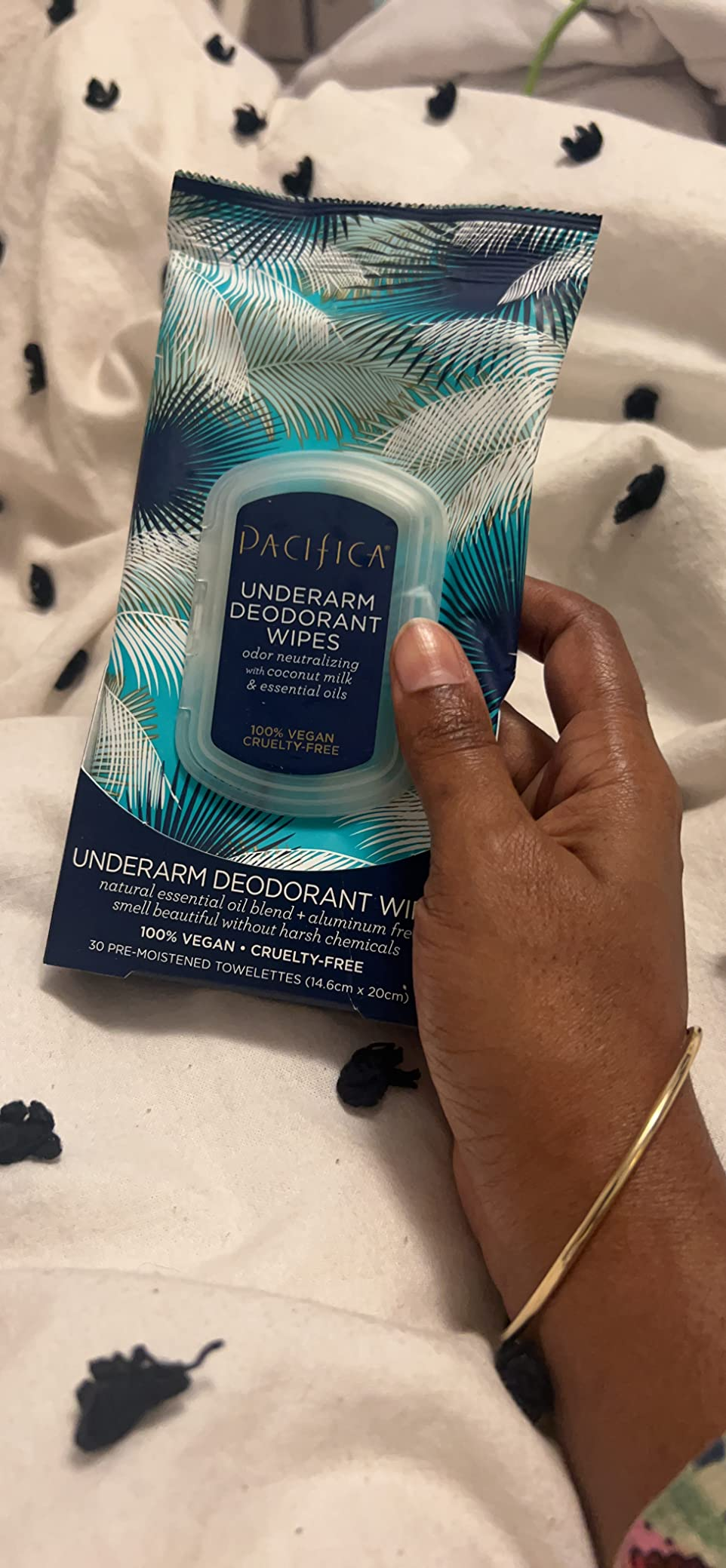 Hand holding Pacifica underarm deodorant wipes successful  blue, tropical-themed packaging