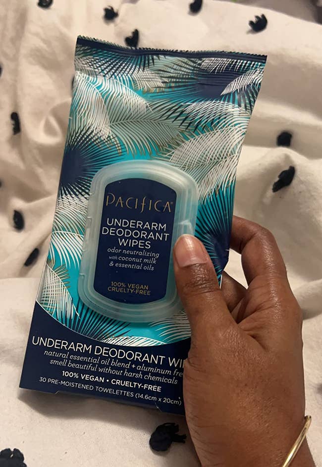 Hand holding Pacifica underarm deodorant wipes successful blue, tropical-themed packaging
