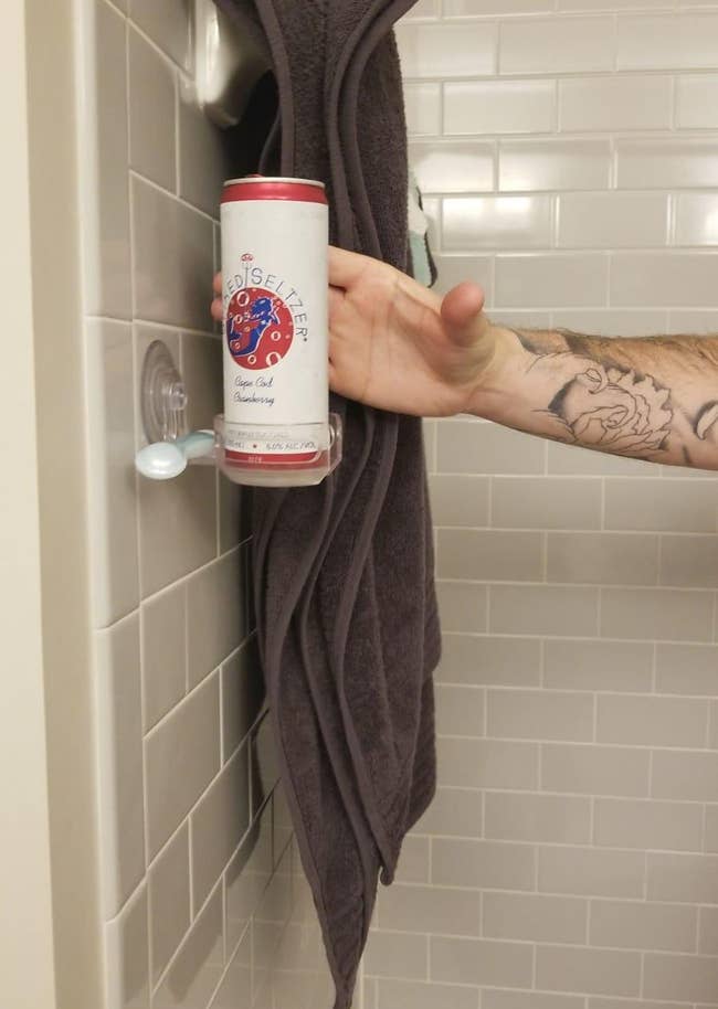 reviewer's hand reaching out from the shower to grab beer can from the holder