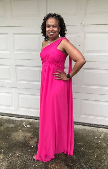 reviewer in elegant one-shoulder pink gown posing with hand on hip