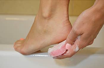 Model using loofah soap on heel of foot