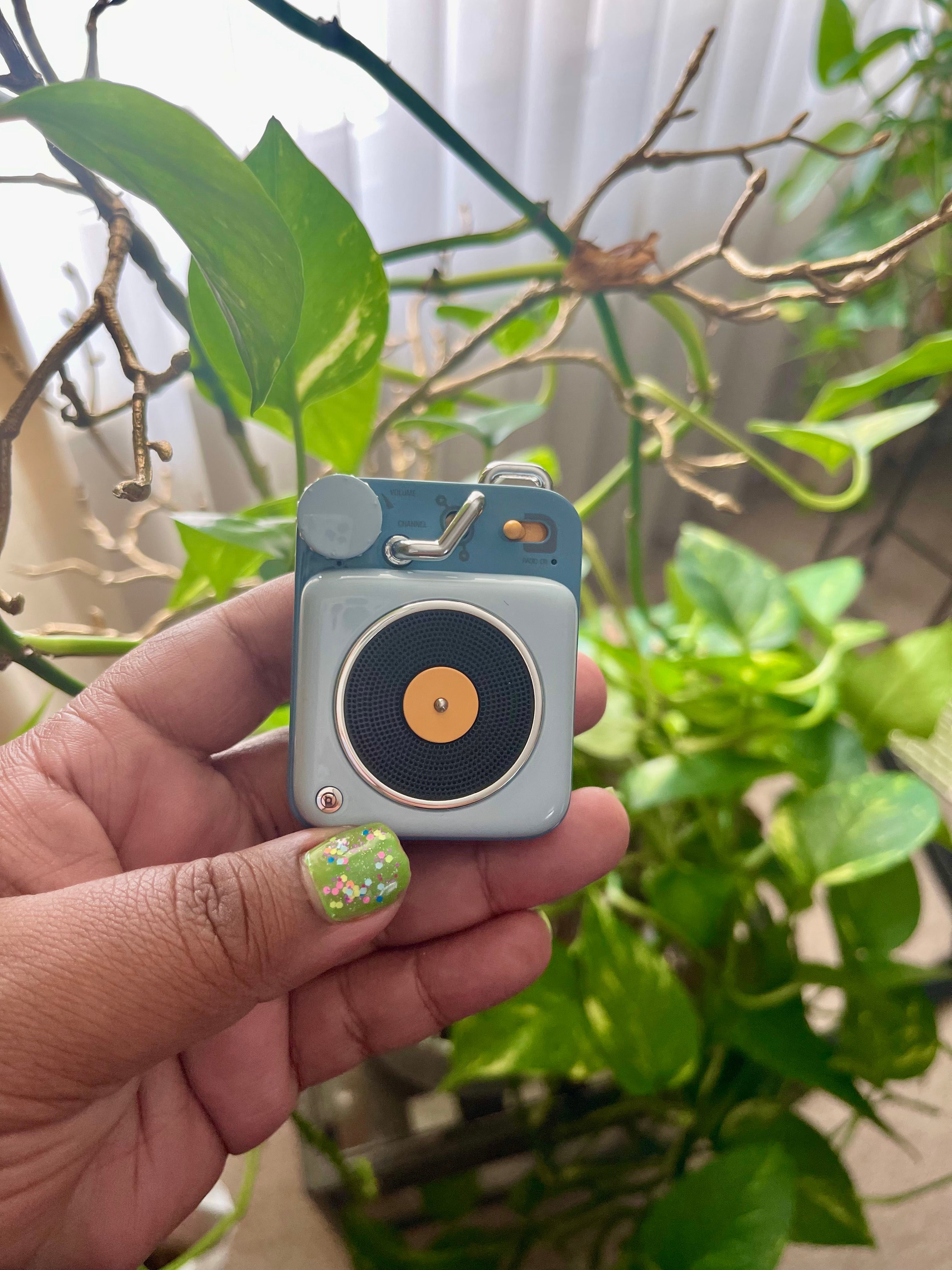 kit holding blue mini portable speaker in hand