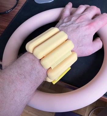 Reviewer wearing the bracelet weights on their arm in yellow color