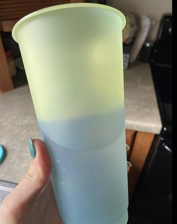 A reviewer holding a green cup that's changing color to blue where the water is 