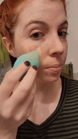 reviewer applying the tinted moisturizer using a sponge