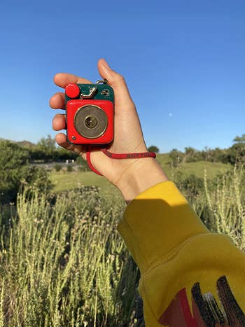 reviewer holding up the red speaker