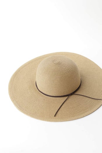 the wide-brim floppy hat in tan straw, with a thin dark brown cord