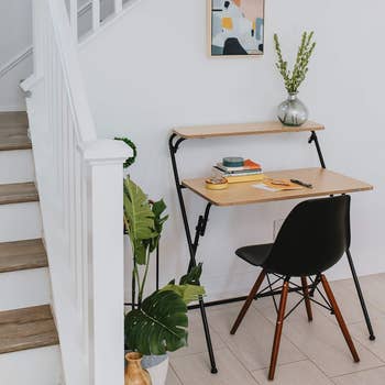 A minimalist home office area with a sleek desk, chair, and decorative plants near a staircase