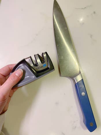 BuzzFeeder holding the knife sharpener next to a kitchen knife