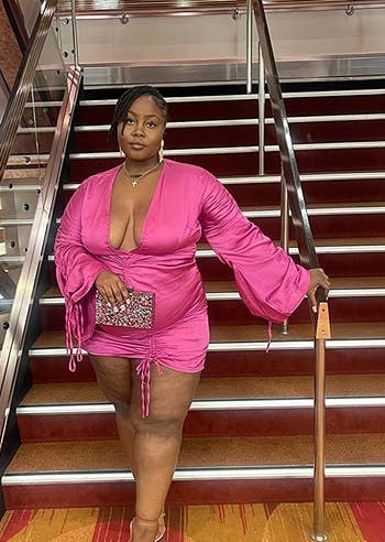 another reviewer in a pink dress holding the multicolored clutch