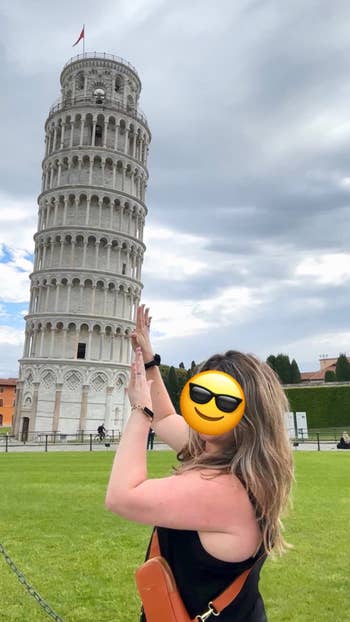 Person posing with hand gesture as if holding the Leaning Tower of Pisa