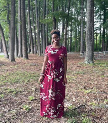 Person in a floral dress standing in a wooded area