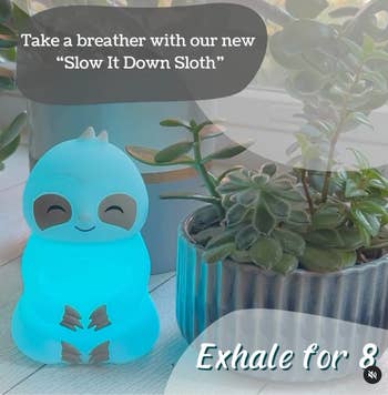 Glowing bluish  sloth-shaped decor point  beside potted plants, with substance   promoting a calming merchandise  called 