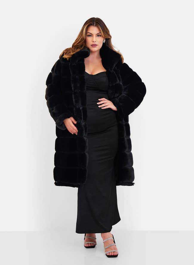 model posing with hand on hip in long, black, puffy faux fur coat