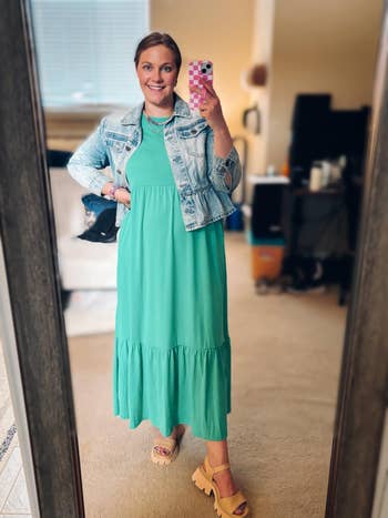 Person successful reflector wearing a denim overgarment and agelong greenish formal with open-toed shoes, holding a pinkish phone. Casual, stylish outfit for shopping